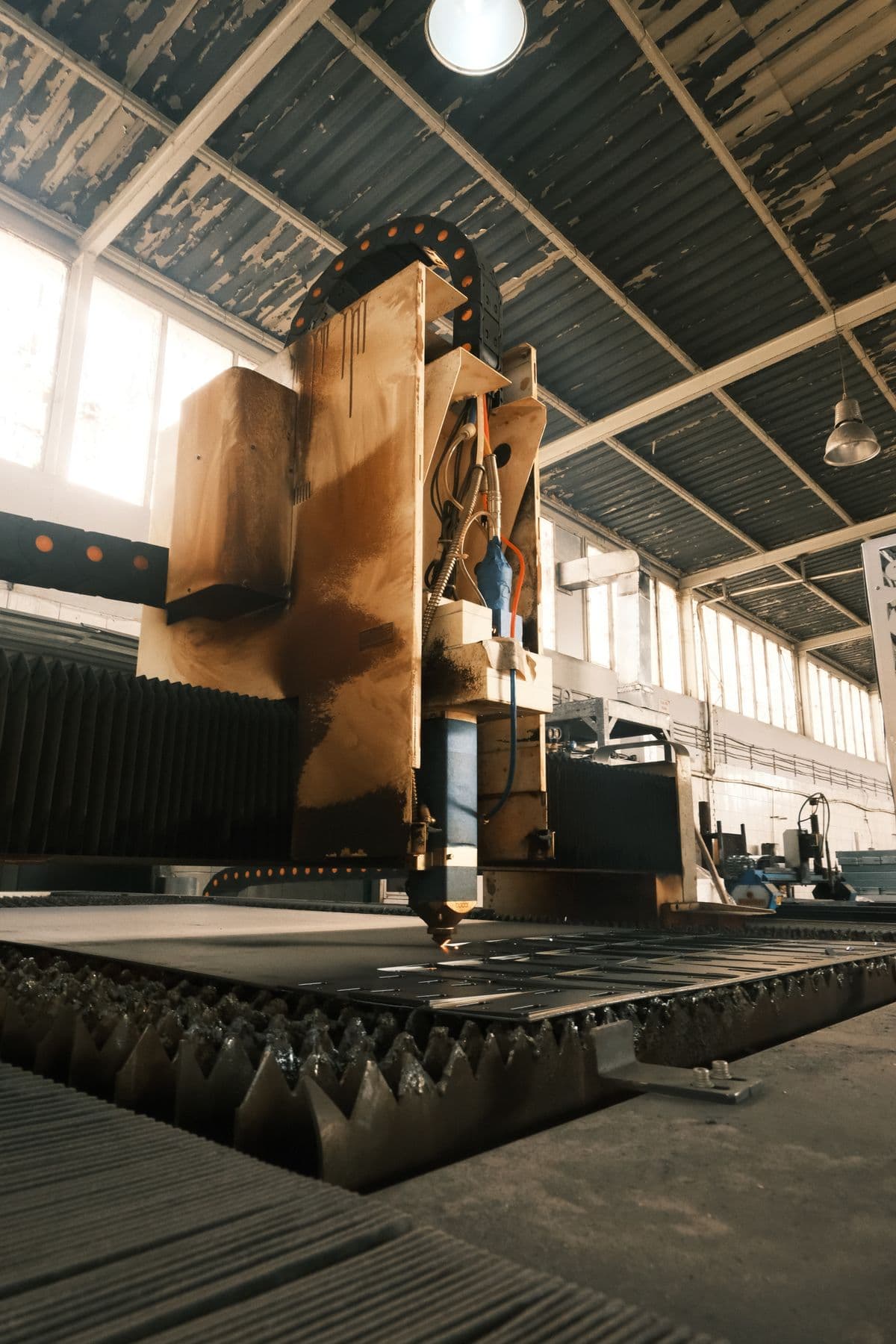 A CNC cutting machine at work on a sunlit production floor.